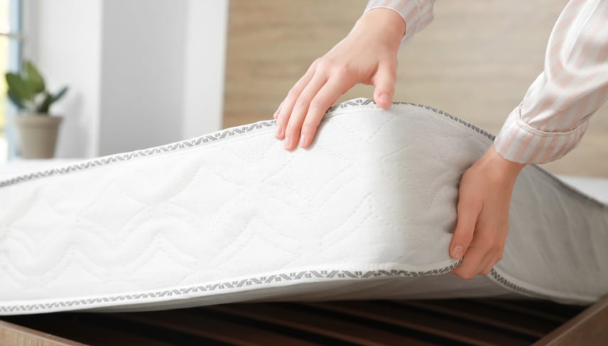 Woman putting soft orthopedic mattress on bed