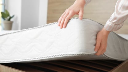 Woman putting soft orthopedic mattress on bed