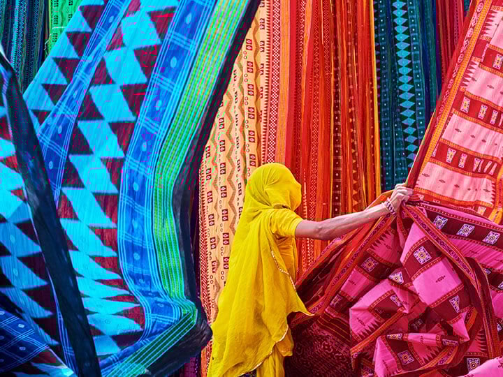 Woman in yellow sari collecting textiles in India