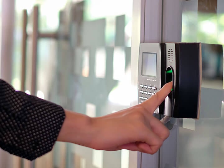 Employee using biometric fingerprint scanner to scan into work and track hours worked