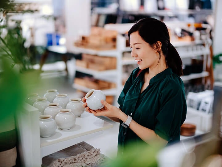 Asian adult female looking at a spherical planting pot in a store