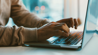 Hands typing on a laptop keyboard. 