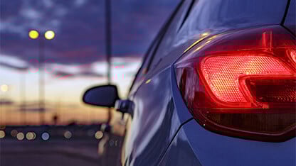 Rear headlight car against defocused background of traffic lights at dusk 