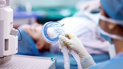 Nurse holding anesthesia mask in operating room