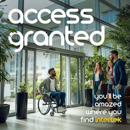 A man entering a building in his wheelchair as a group of friends greet him from within
